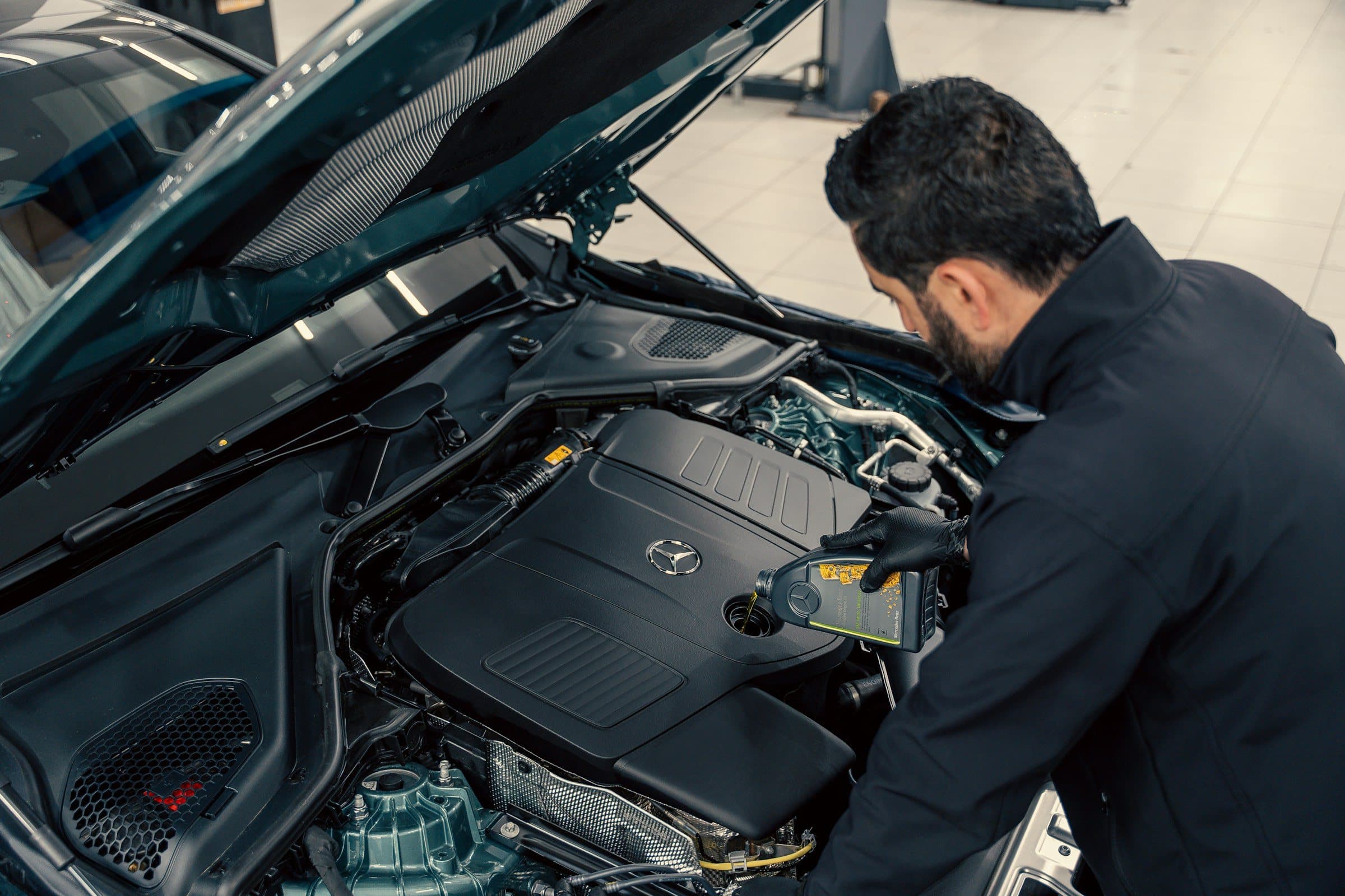 A technician checking an engine under an open hood.