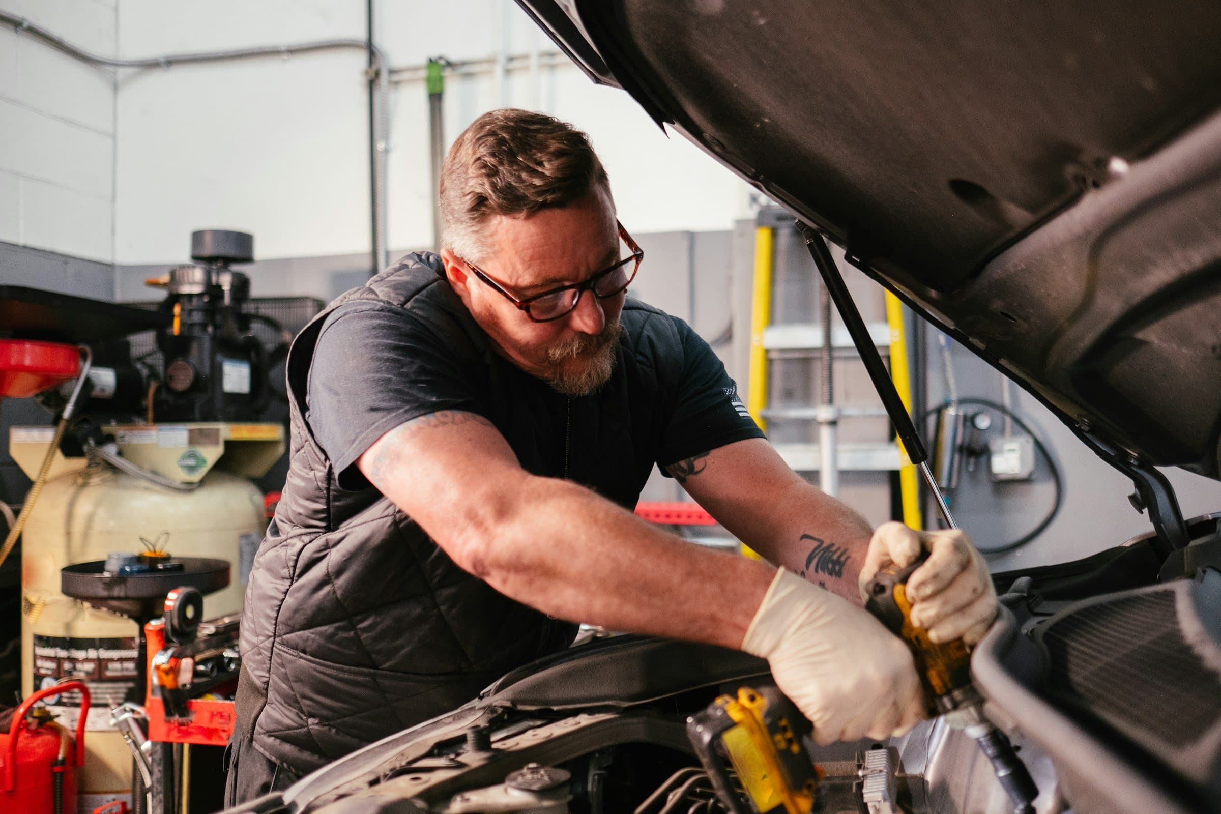 A mechanic at work under the hood of a car.